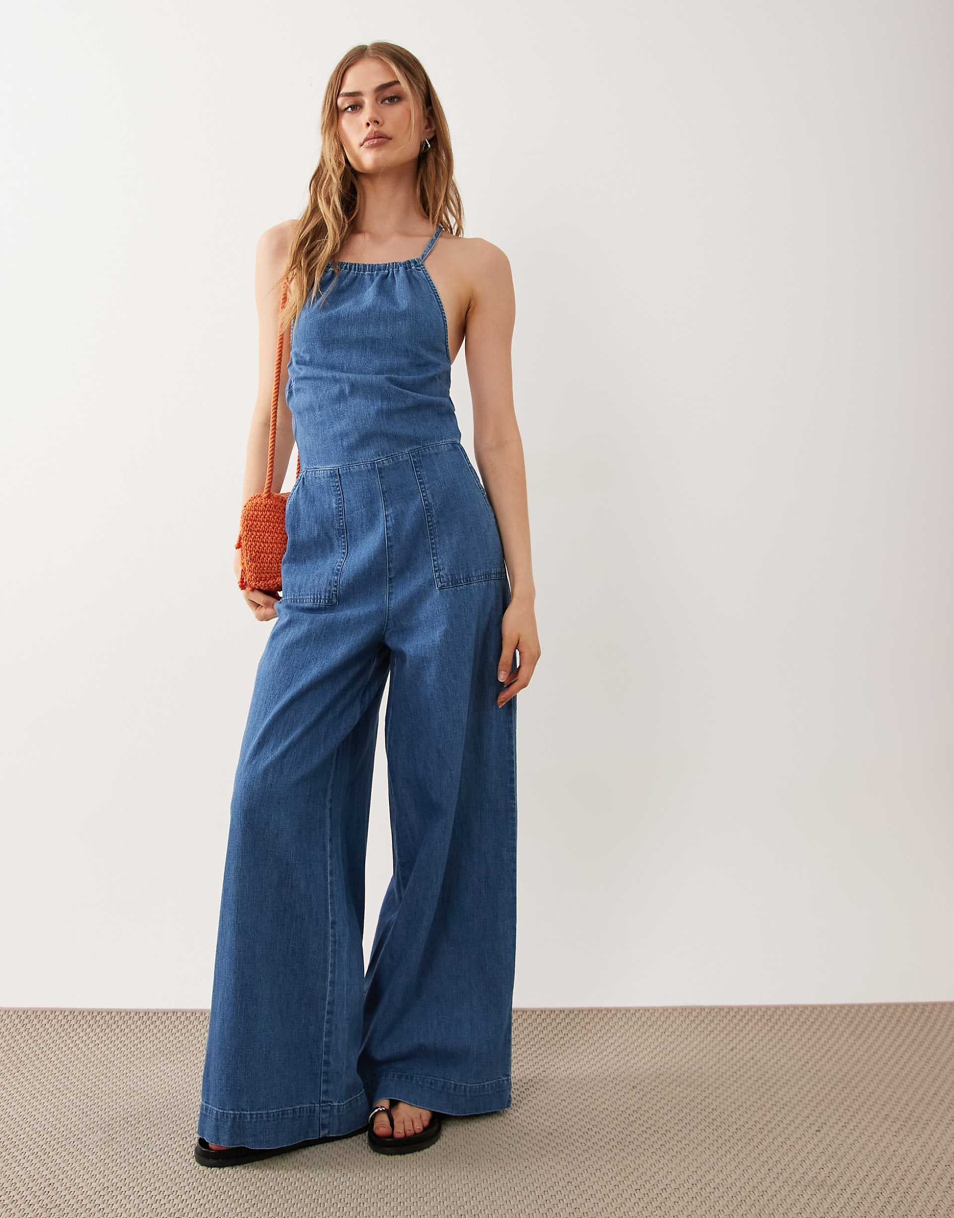 ASOS DESIGN halter neck denim jumpsuit with patch pockets in midwash